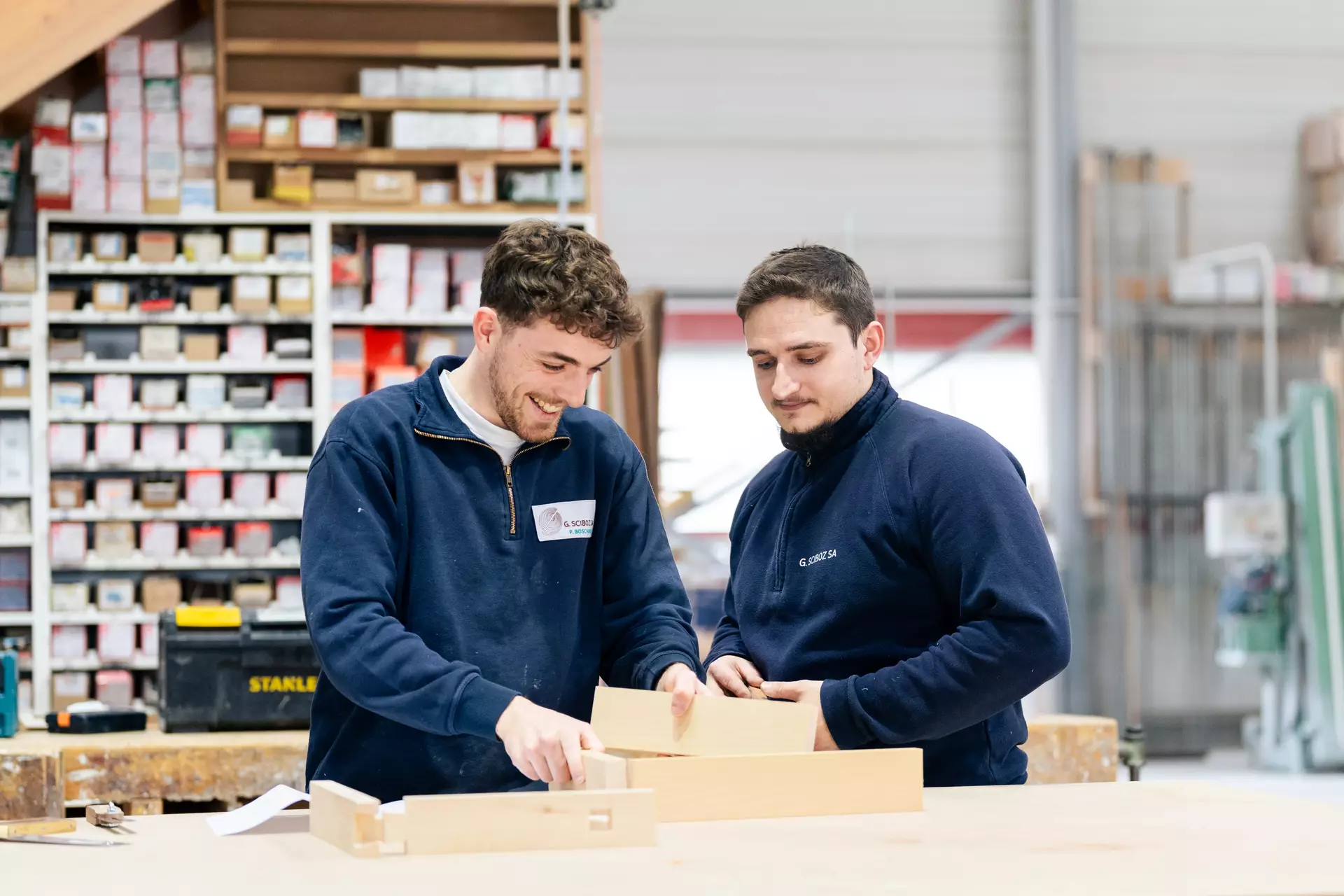 Apprenti et formateur charpentier en souriant tout en échangeant autour d'un projet