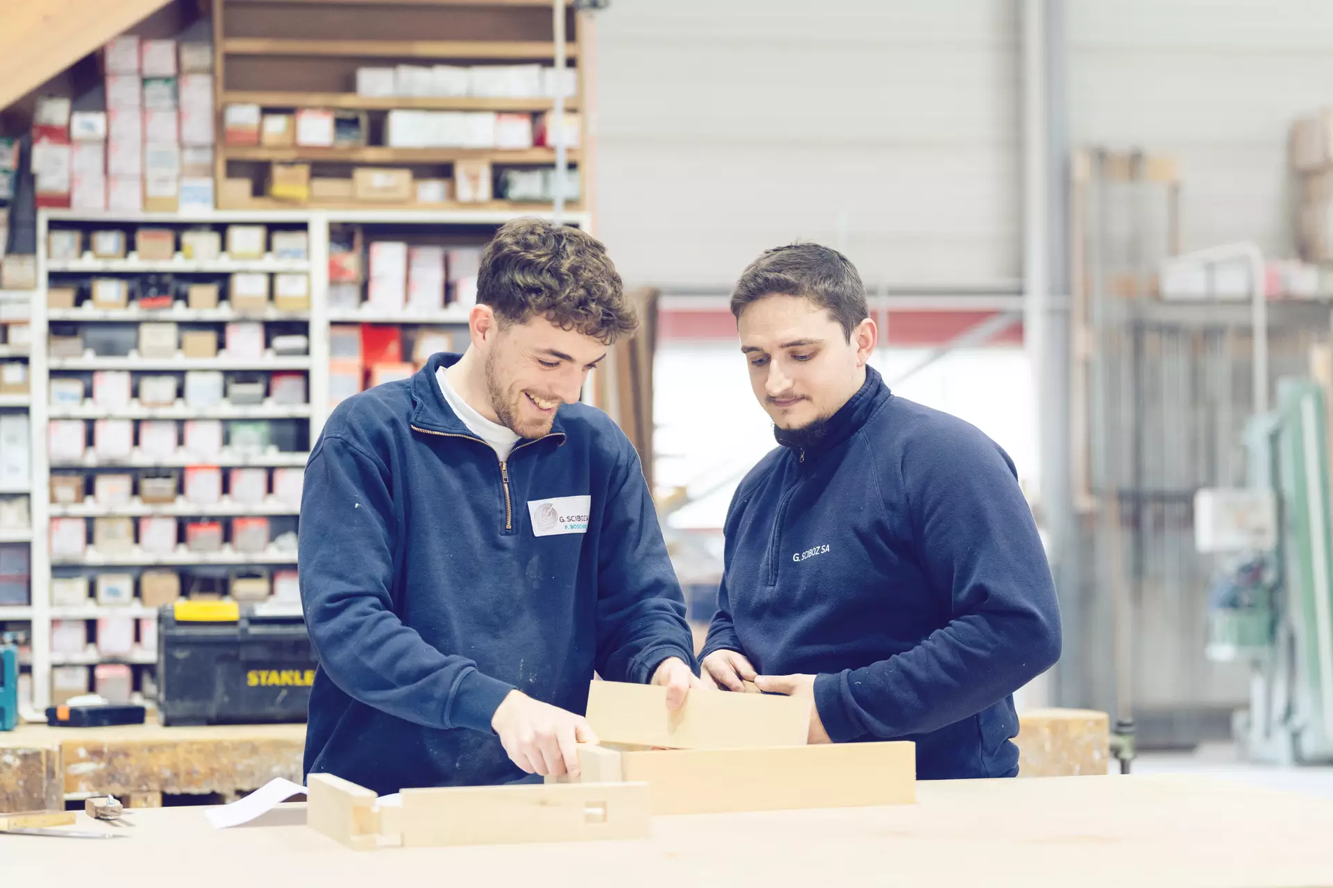 Apprenti et formateur charpentier en souriant tout en échangeant autour d'un projet