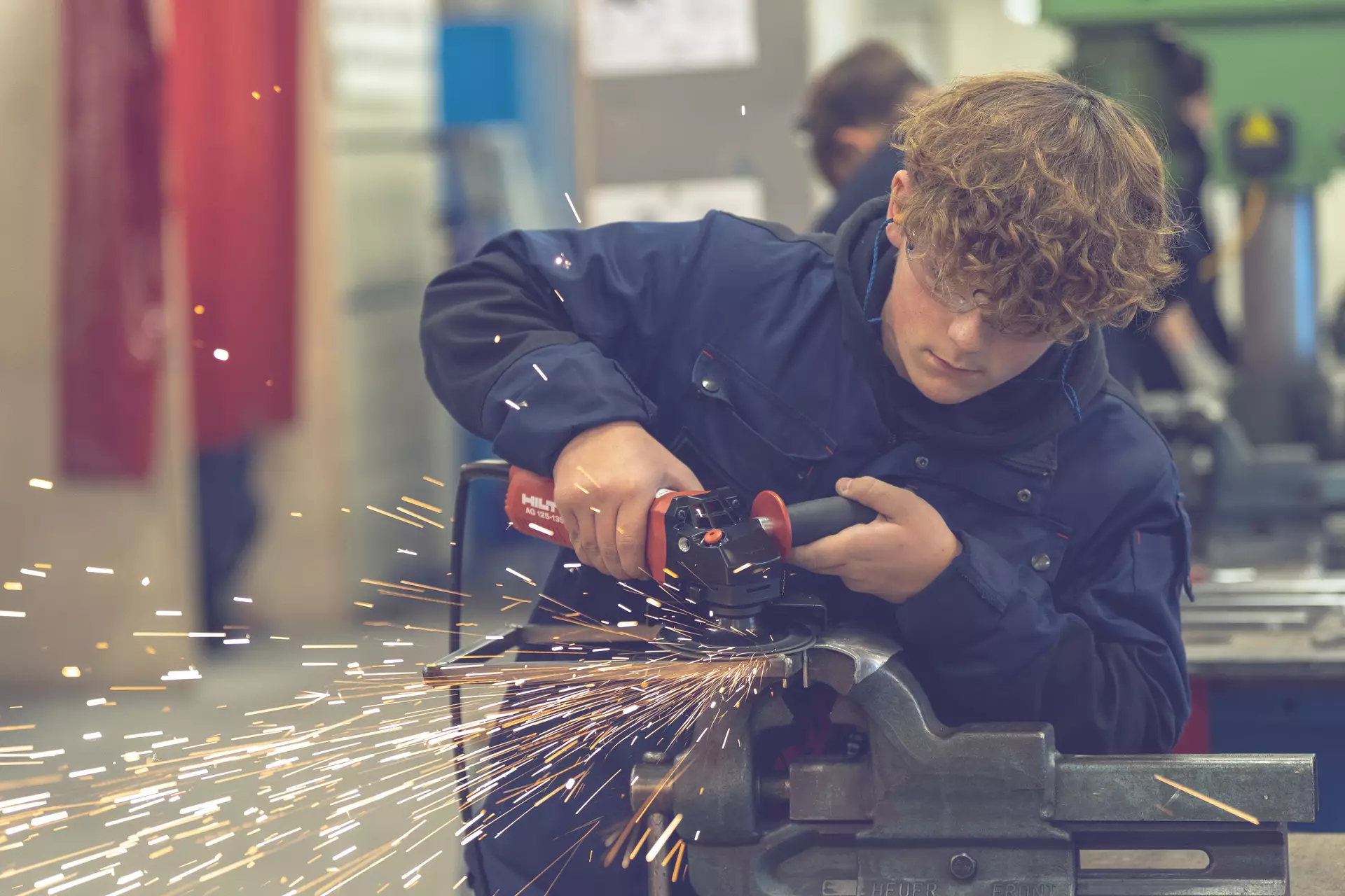 garçon constructeur métallique utilisant un appareil sur une pièce. des étincelles giclent.