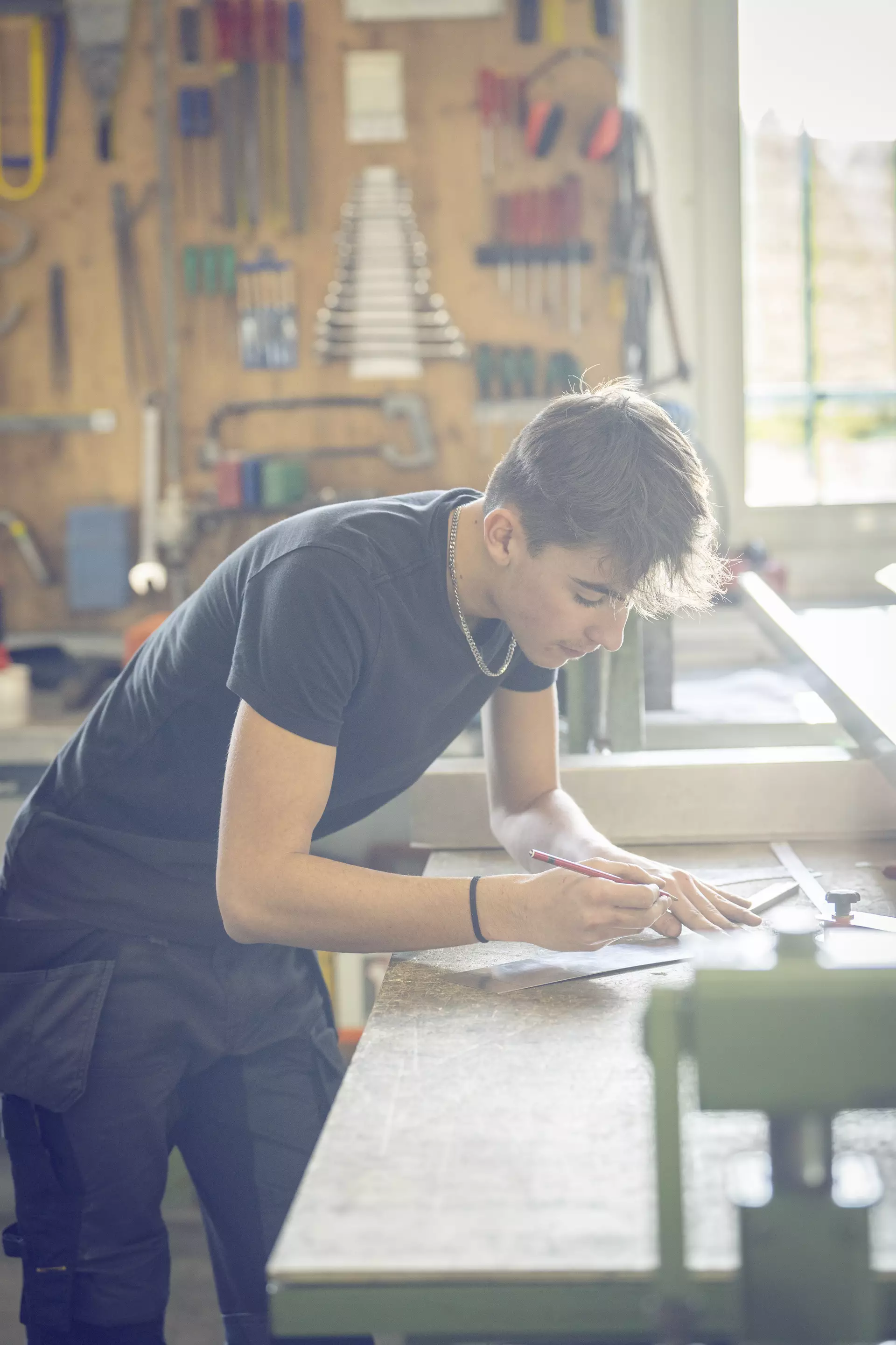 apprenti ferblantier découpant une pièce sur une place de travail