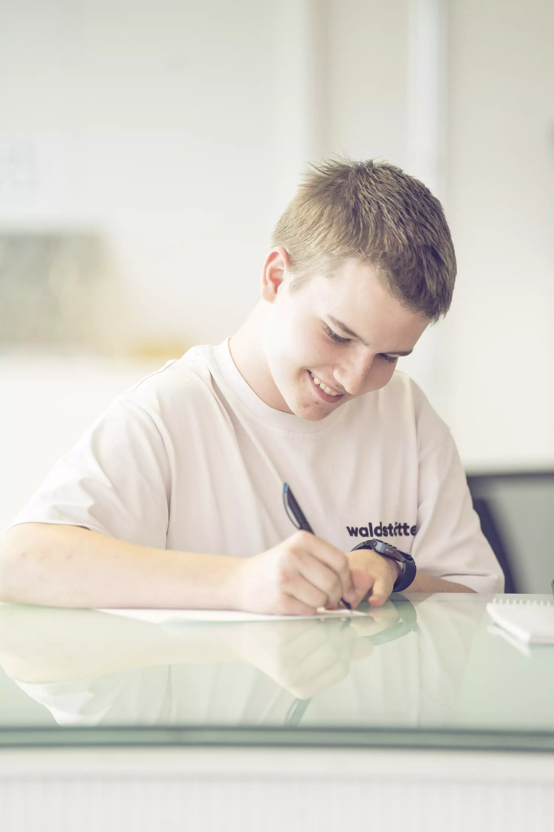 Apprenti dessinateur en batiment écrivant accoudé à une table haute