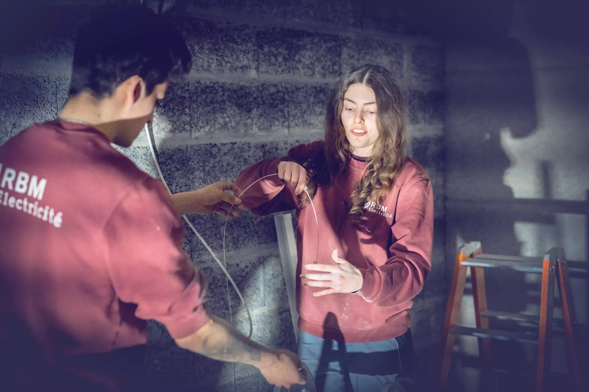 Apprentie électricienne et formateur sur un chantier préparant une installation