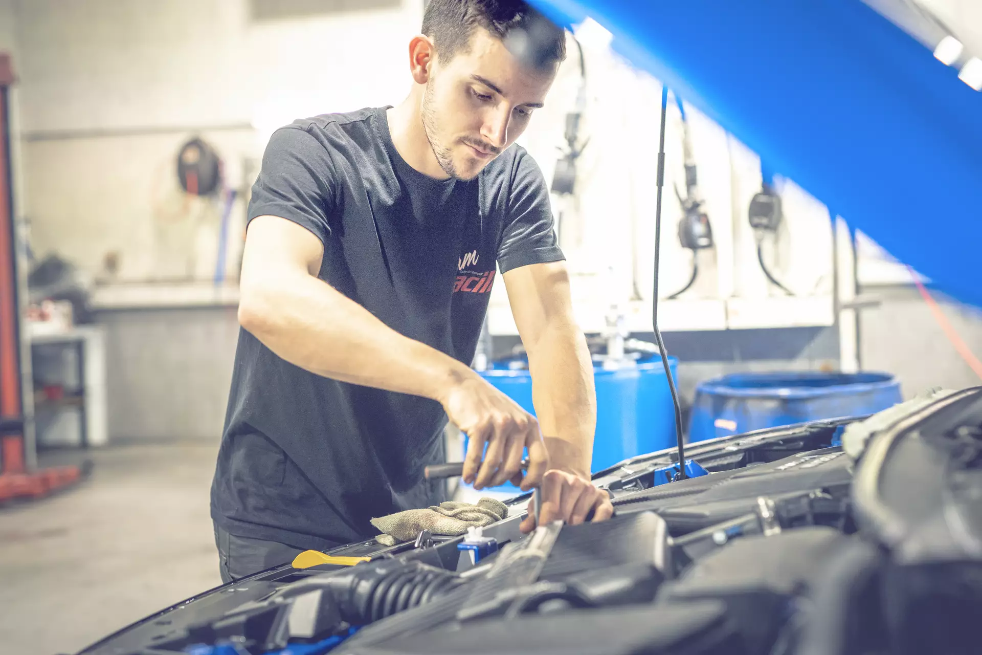 Apprenti mécanicien sous un capot en train de travailler