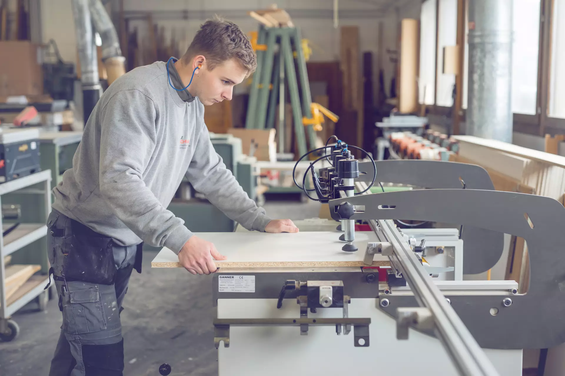 apprenti menuisier en train de serré une planche
