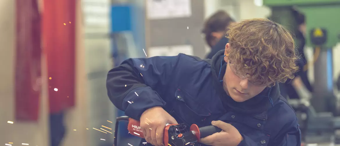 garçon constructeur métallique utilisant un appareil sur une pièce. des étincelles giclent.
