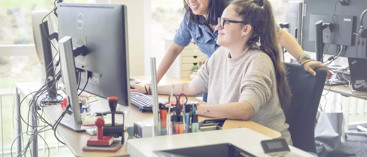 apprentie employée de commerce et sa formatrice devant un ordinateur