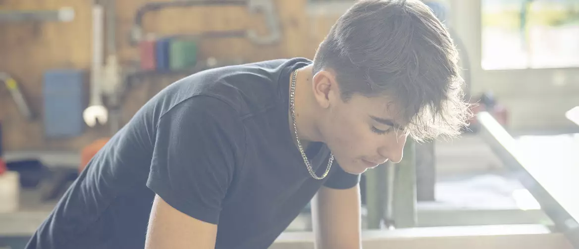 apprenti ferblantier découpant une pièce sur une place de travail