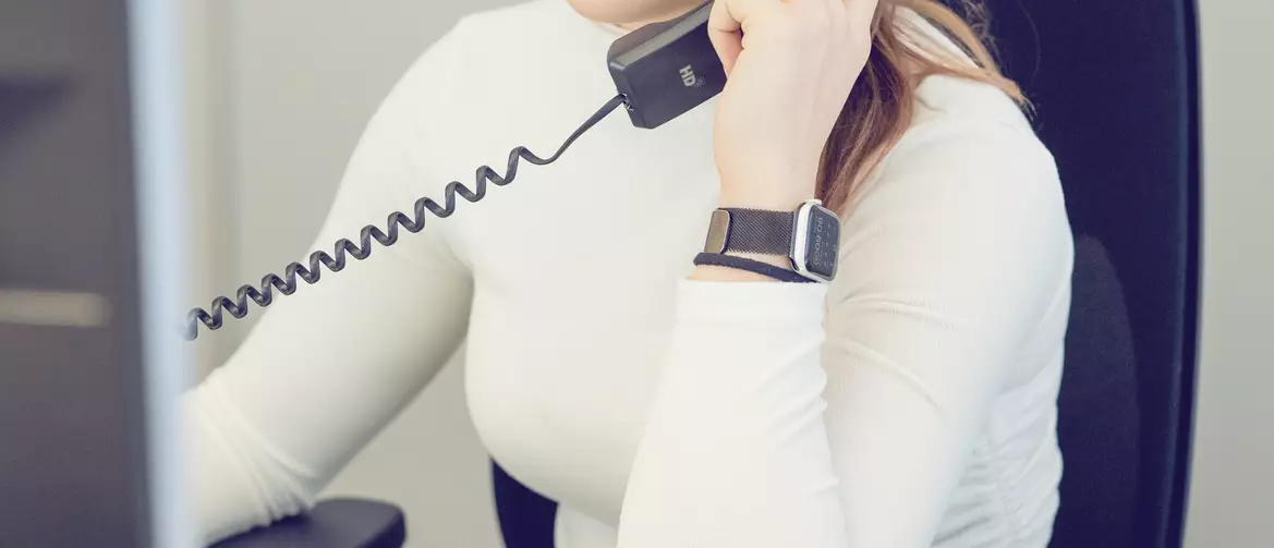 Apprentie employée de commerce au téléphone devant son ordinateur