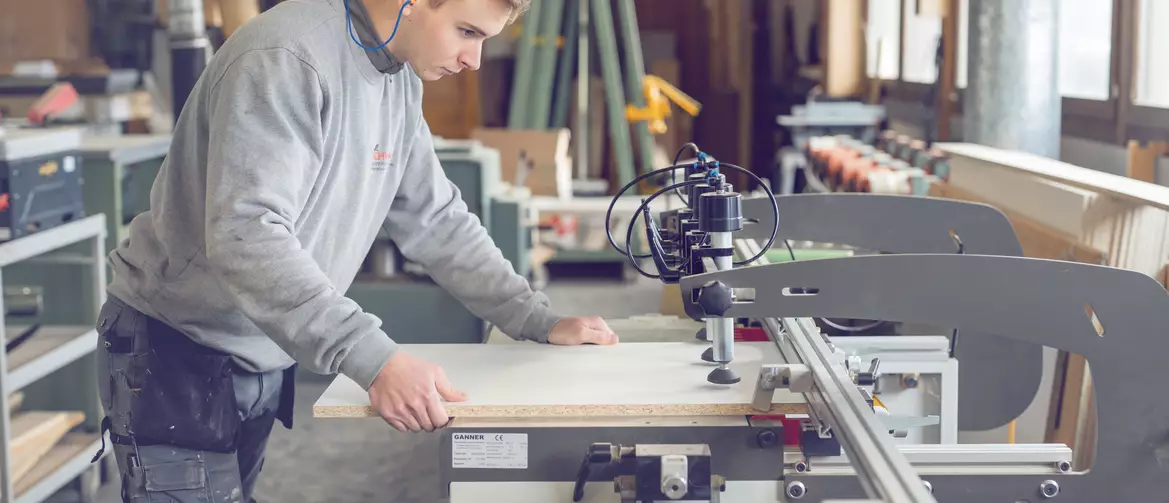 apprenti menuisier en train de serré une planche