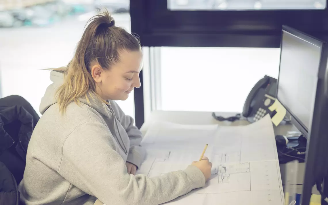 dessinatrice sur métal dessinant à la main seul devant son poste de travail