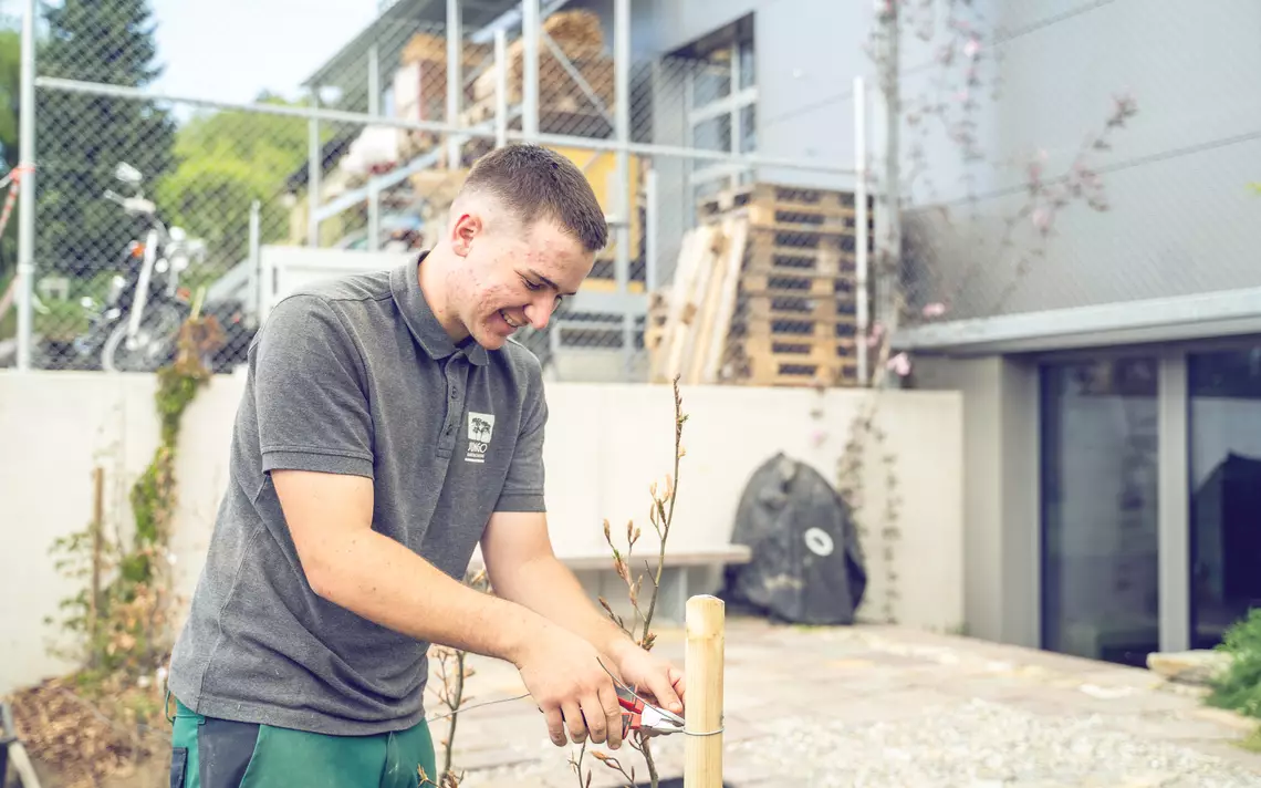 Apprenti paysagiste en train de fixer une barrière